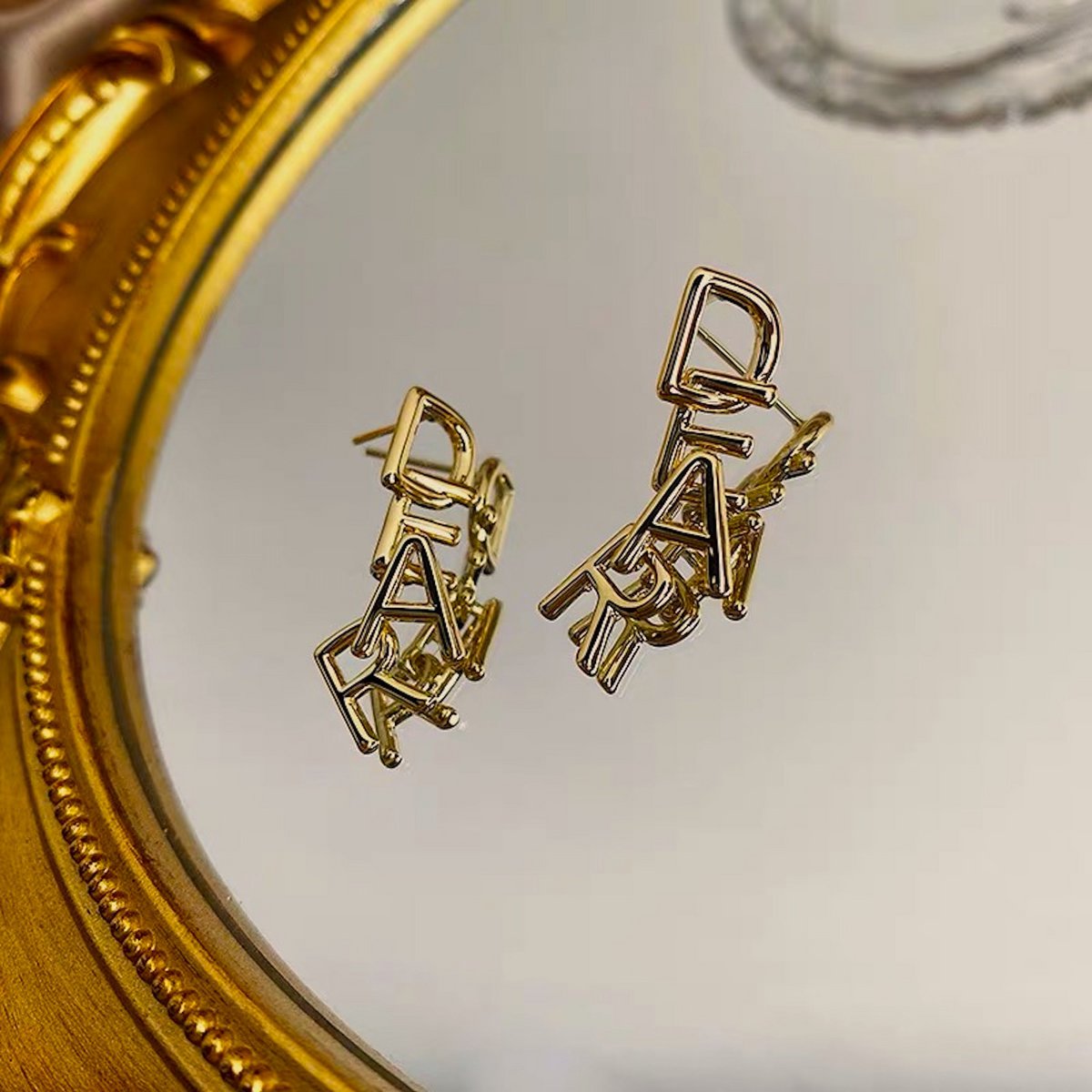Met elkaar verweven DEAR-letters: romantische gouden oorbellen met een speelse, minimalistische essentie