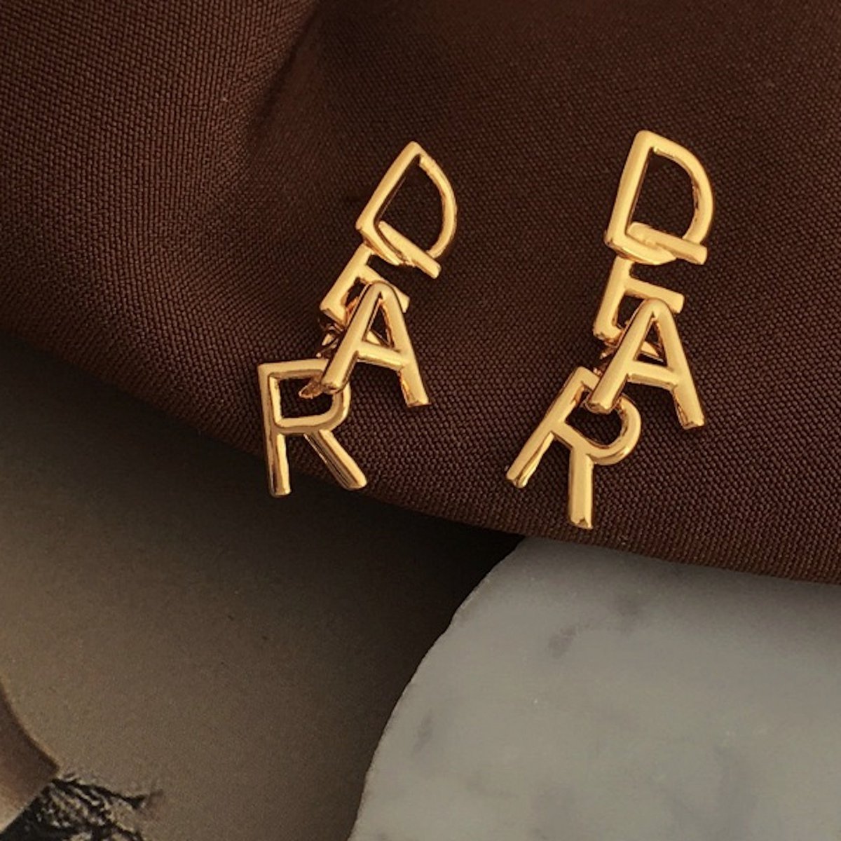 Met elkaar verweven DEAR-letters: romantische gouden oorbellen met een speelse, minimalistische essentie